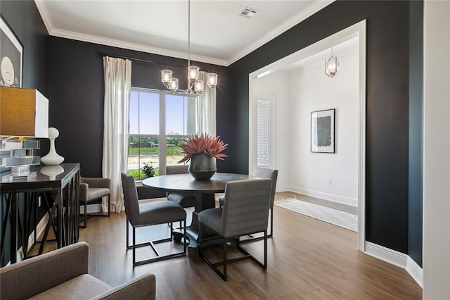 dining room with hardwood / wood-style floors, ornamental molding, and an inviting chandelier