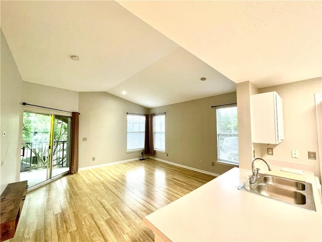 kitchen featuring sink, light wood-type flooring, white cabinets, and a wealth of natural light