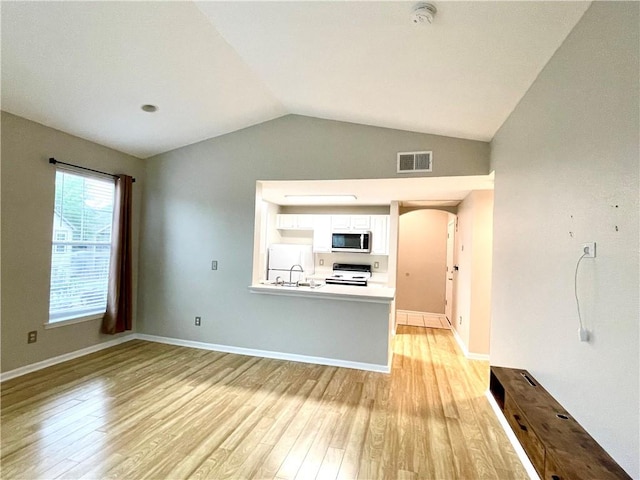 unfurnished living room with vaulted ceiling, sink, and light wood-type flooring