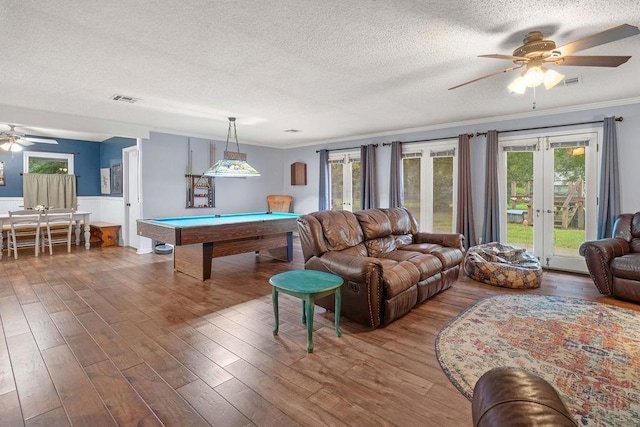living room featuring billiards, hardwood / wood-style floors, ornamental molding, a textured ceiling, and french doors
