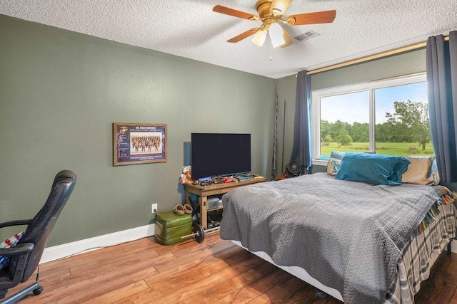 bedroom featuring ceiling fan, wood-type flooring, and a textured ceiling