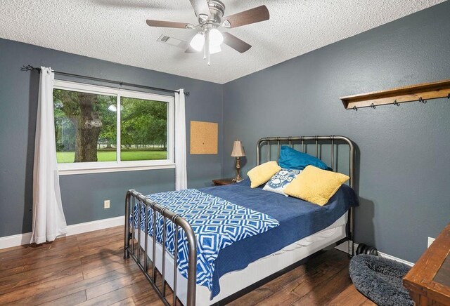 bedroom with dark hardwood / wood-style flooring, ceiling fan, and a textured ceiling