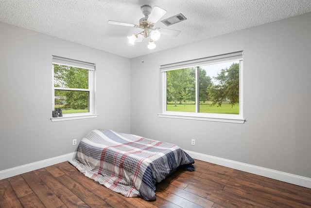 bedroom featuring ceiling fan, hardwood / wood-style flooring, and a textured ceiling