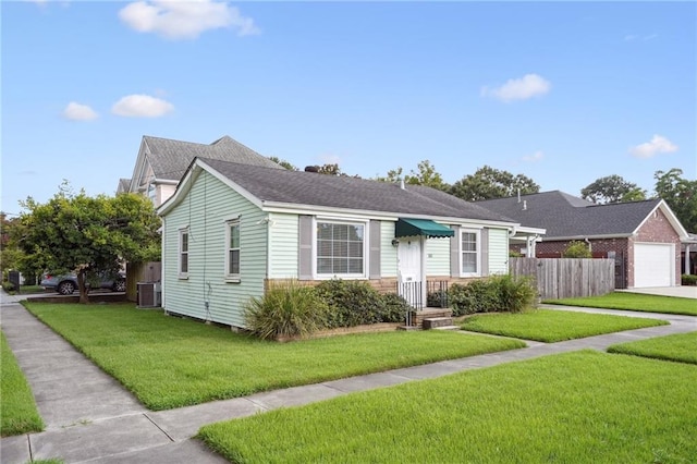 view of front of house featuring a garage, central AC, and a front lawn