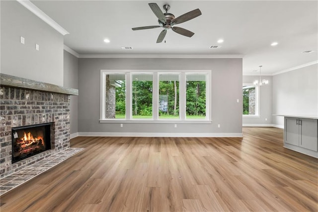 unfurnished living room featuring crown molding, a fireplace, ceiling fan with notable chandelier, and light hardwood / wood-style flooring