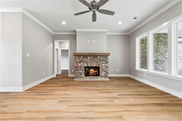 unfurnished living room featuring light hardwood / wood-style floors, ornamental molding, a brick fireplace, and ceiling fan