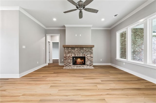 unfurnished living room with crown molding, a brick fireplace, ceiling fan, and light wood-type flooring