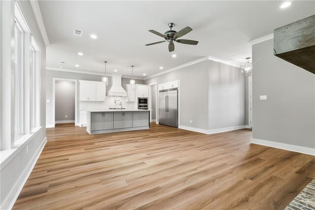 unfurnished living room with crown molding, light hardwood / wood-style flooring, sink, and ceiling fan