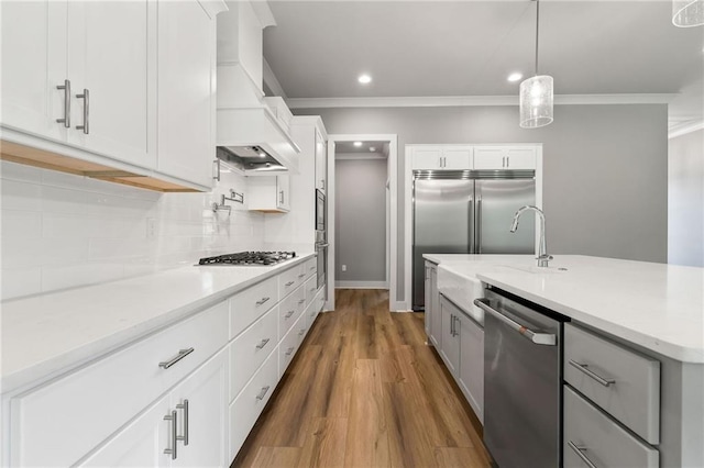 kitchen with decorative light fixtures, white cabinets, backsplash, stainless steel appliances, and custom range hood