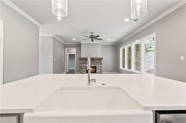 kitchen with pendant lighting, ceiling fan, a fireplace, and sink