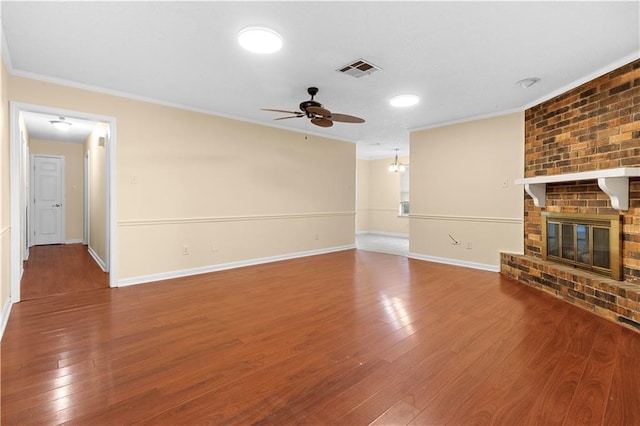 unfurnished living room with ceiling fan, a brick fireplace, brick wall, hardwood / wood-style flooring, and ornamental molding