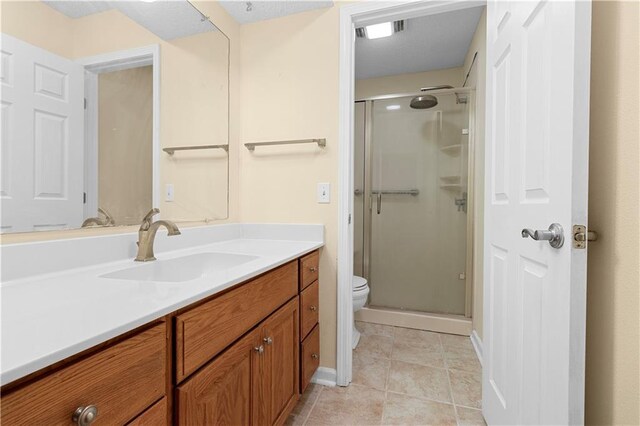 bathroom featuring tile patterned floors, vanity, an enclosed shower, and toilet