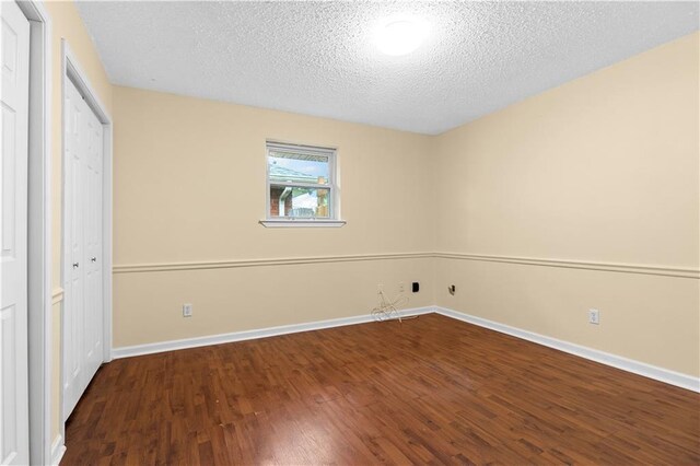 unfurnished bedroom featuring a textured ceiling and dark wood-type flooring