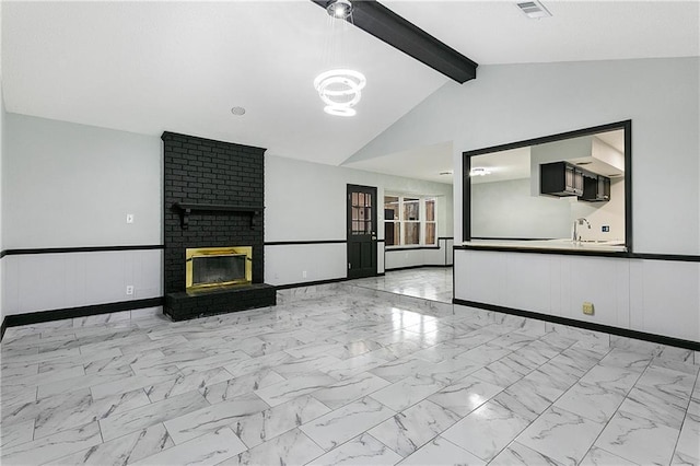 unfurnished living room with sink, a fireplace, and lofted ceiling with beams