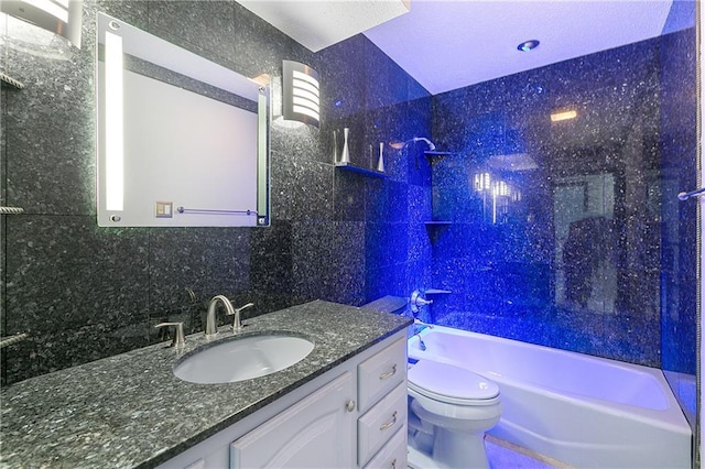 full bathroom with toilet, tasteful backsplash, tile walls, vanity, and tiled shower / bath combo