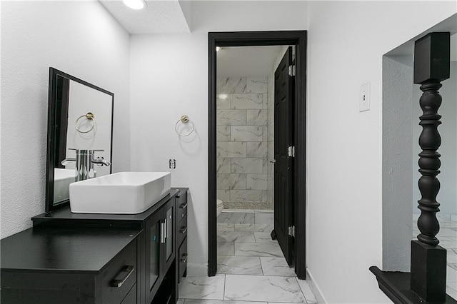 bathroom with vanity, tiled shower, and toilet