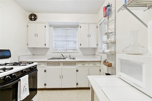 220200 Nashville Ave, New Orleans, LA 70115 - kitchen featuring range with gas cooktop, white microwave, light countertops, white cabinetry, and a sink