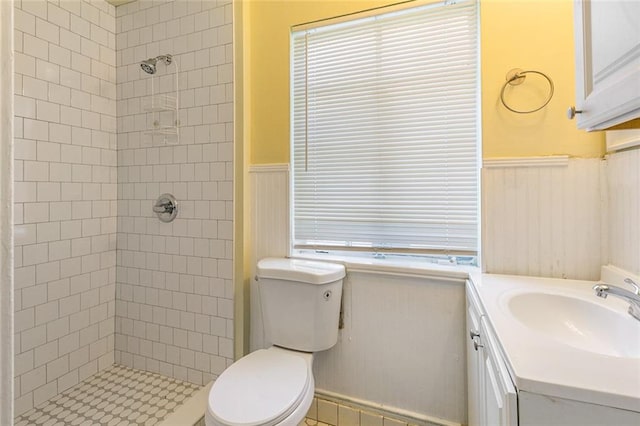 bathroom with toilet, vanity, and a tile shower