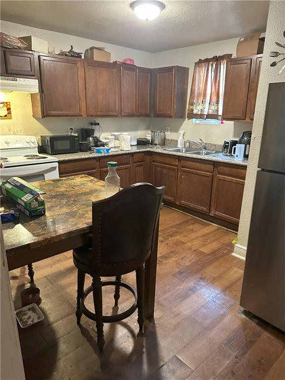 kitchen featuring white electric range, stainless steel fridge, a textured ceiling, dark hardwood / wood-style flooring, and sink