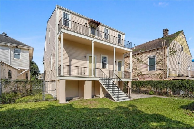 rear view of house featuring a balcony and a lawn