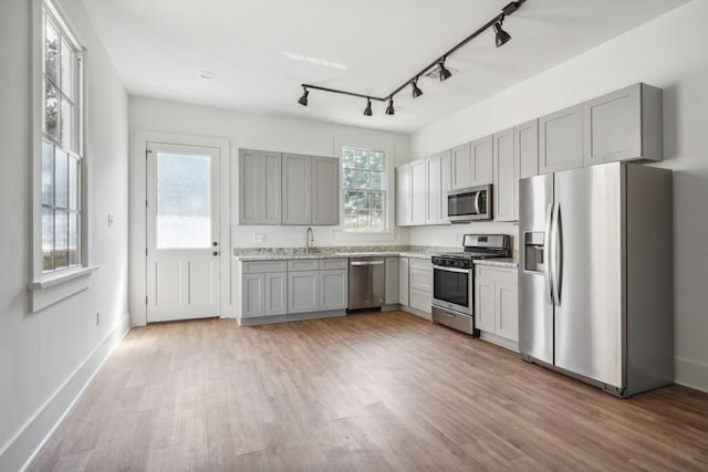 kitchen with gray cabinets, appliances with stainless steel finishes, sink, and light wood-type flooring