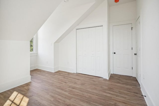 additional living space with hardwood / wood-style flooring and vaulted ceiling