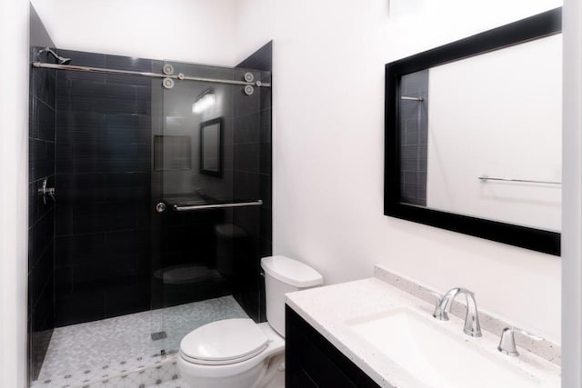 bathroom featuring vanity, toilet, and a tile shower