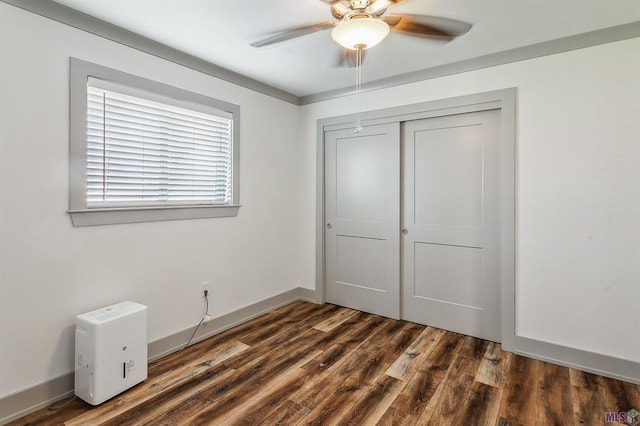 unfurnished bedroom featuring dark wood-type flooring, ceiling fan, and a closet