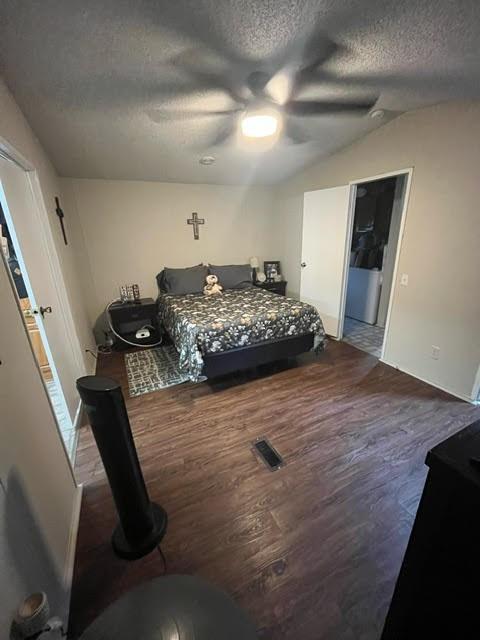 bedroom with hardwood / wood-style flooring, a textured ceiling, lofted ceiling, and ceiling fan