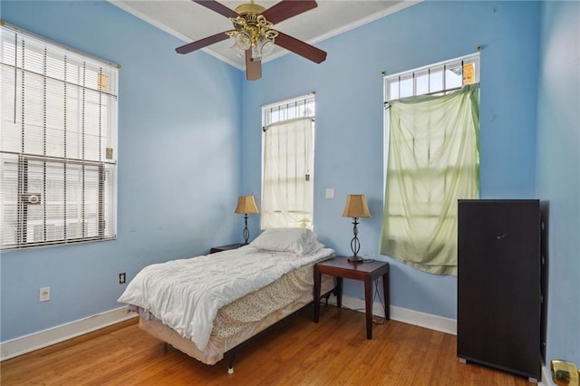 bedroom featuring ornamental molding, multiple windows, hardwood / wood-style flooring, and ceiling fan