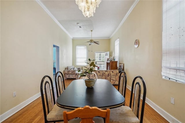 dining area featuring light wood-type flooring, ceiling fan with notable chandelier, and ornamental molding