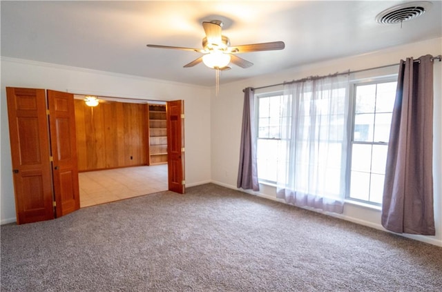 spare room with crown molding, light carpet, and ceiling fan