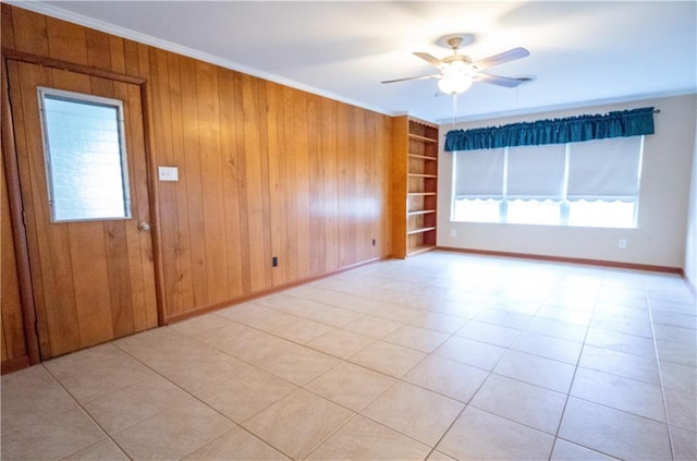 tiled empty room with ornamental molding, wood walls, ceiling fan, and built in features