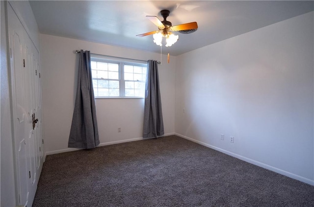 spare room featuring dark colored carpet and ceiling fan