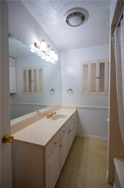 bathroom featuring a textured ceiling, tile patterned flooring, and vanity