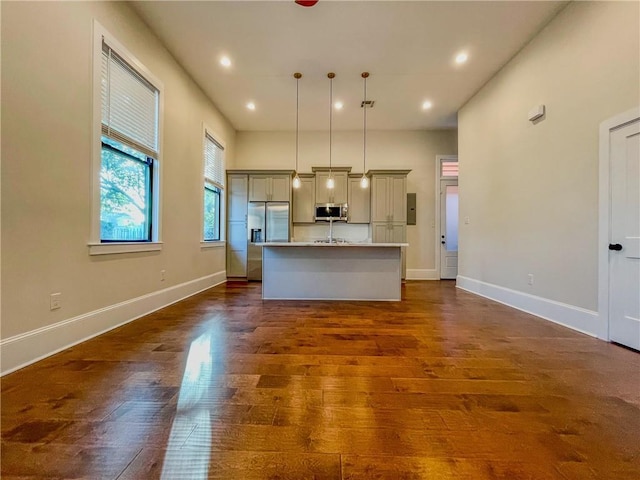 kitchen with dark wood-style floors, a kitchen island with sink, stainless steel microwave, and gray cabinets