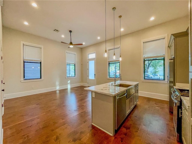 kitchen featuring decorative light fixtures, ceiling fan, stainless steel appliances, an island with sink, and dark wood-type flooring