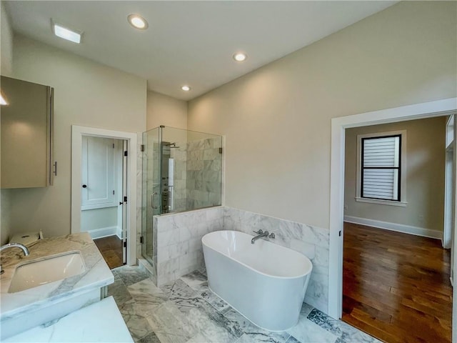 bathroom with plus walk in shower, sink, and wood-type flooring