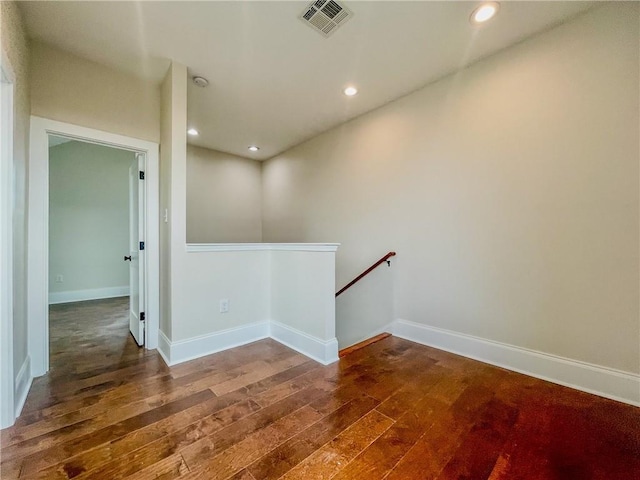 empty room featuring dark wood-style floors, baseboards, visible vents, and recessed lighting