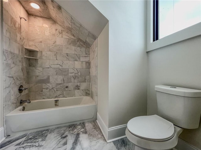 bathroom featuring tiled shower / bath, tile patterned flooring, and toilet