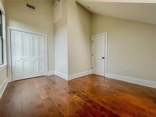 unfurnished room with high vaulted ceiling, wood finished floors, visible vents, and baseboards