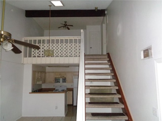 staircase with a skylight, beam ceiling, and tile patterned floors