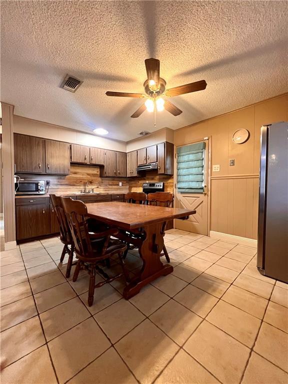 tiled dining room featuring ceiling fan, sink, and a textured ceiling