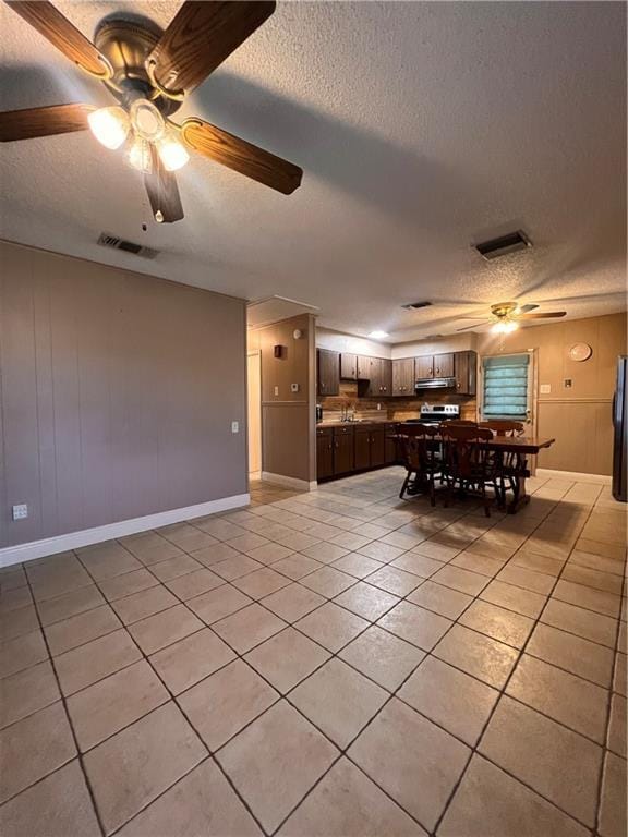 unfurnished dining area with light tile patterned flooring, ceiling fan, and a textured ceiling