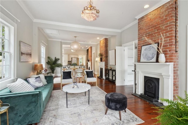 living room with dark hardwood / wood-style floors, crown molding, brick wall, and an inviting chandelier