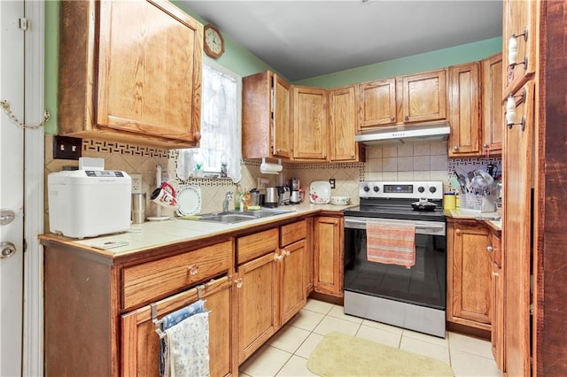 kitchen with stainless steel electric range oven, sink, light tile patterned floors, and backsplash