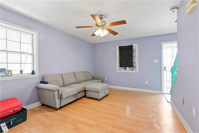 living room featuring ceiling fan, plenty of natural light, and light hardwood / wood-style floors