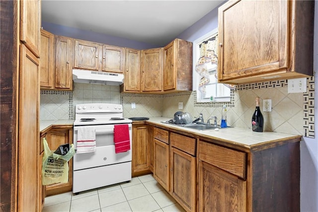 kitchen featuring sink, light tile patterned floors, backsplash, white range with electric stovetop, and tile countertops