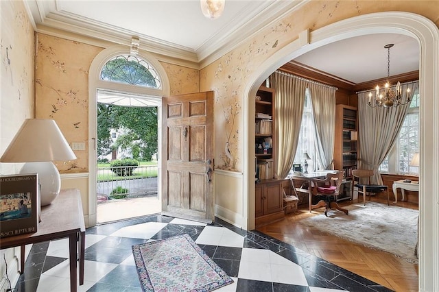 entrance foyer with a chandelier, dark parquet flooring, and ornamental molding