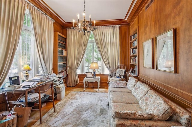 living area with a healthy amount of sunlight, an inviting chandelier, and ornamental molding